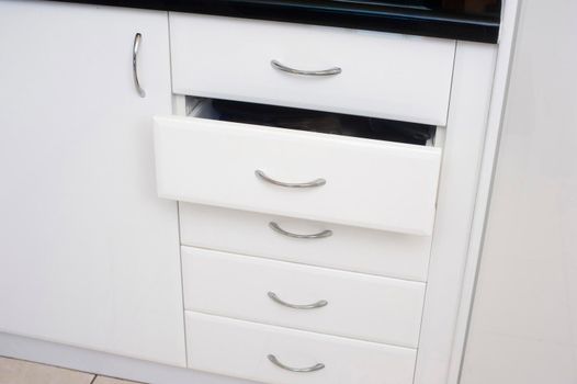 Set of white kitchen drawers in a built in cabinet unit with one drawer slightly open