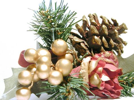 Pine cone Christmas decoration with a red rose, gold berries and green foliage to decorate the Xmas tree or table for dinner