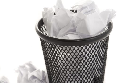 Wastepaper bin filled to overflowing with crumpled white paper