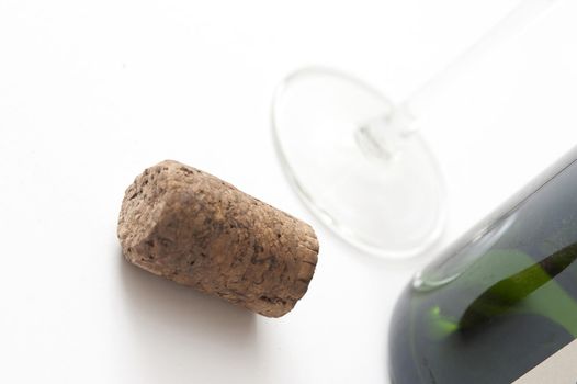 Close Up of Cork Beside Wine Bottle and Glass on White Background in Studio
