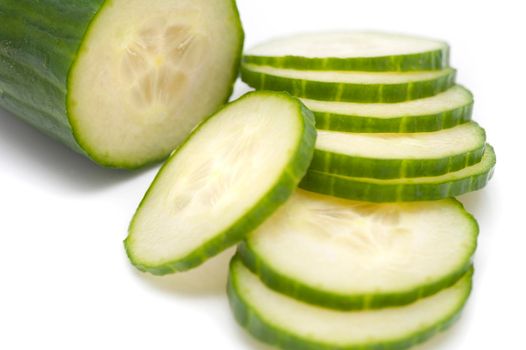 Close-up of a fresh nutritious cucumber with cut slices, on white background