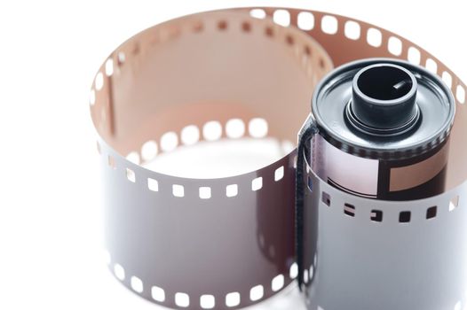 Close Up Still Life of 35mm Film Cannister with Exposed Film Unfurling on White Background with Copy Space - Film and Photography Concept Image