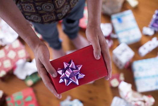 A close up, point of view shot of a teenager handing a Christmas gift.