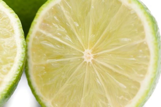 Halved lime detail showing the texture of the juicy pulp, rind and segments over a white background