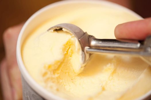 Man serving tasty creamy vanilla Ice cream in a bowl with a metal scoop, close up view