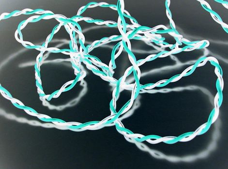 Glowing bright twisted wire of cyan and white colors reflecting in glass surface, close-up background concept