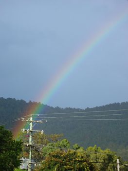 a rainbow ending over a pole mounted power transformer