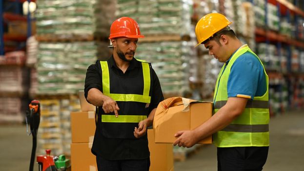 Storehouse employees workers in hardhats and and vests working together in warehouse. Logistics, and manufacture storehouse occupation concept.