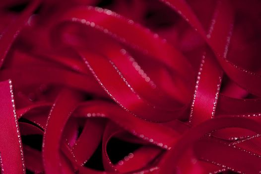 Full frame background of twisted red ribbons with little gold trim on sides with copy space