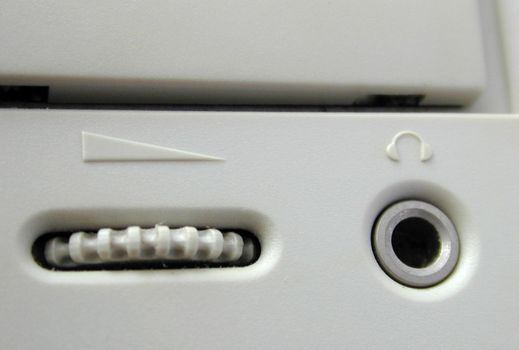 Close up detail of a ridged CD ROM volume control knob on a white machine in a technology, data storage and entertainment concept