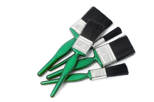 Set of new paint brushes with colorful green handles for painting a building interior lying on a white background with copyspace in a DIY and renovation concept