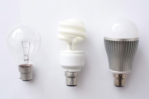 Three options for electric lighting with LED, fluorescent and incandescent light bulbs in a row over white