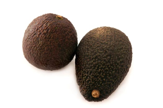 Two whole fresh ripe avocado pears, Persea americana, with one viewed on its side and the other from the top over white