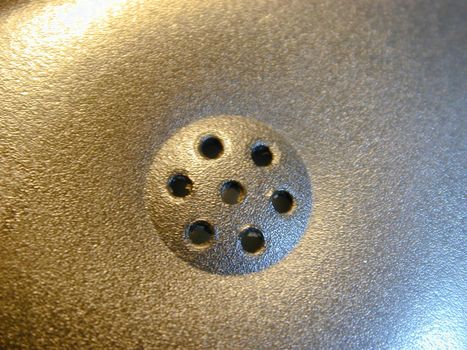 Macro close up on telephone earpiece section speaker with seven little holes in the middle