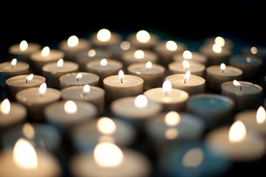 Seasonal background with an array of burning Christmas candles with festive twinkling flames on a black background with shallow dof