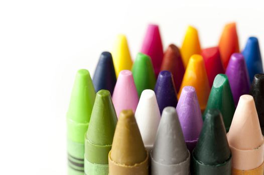 Collection of colored wax crayon points in the colors of the spectrum viewed close up with shallow DOF over white with copy space