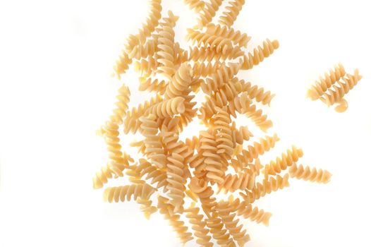Spiral twist uncooked dried Italian pasta scattered on a white background with copyspace viewed from above