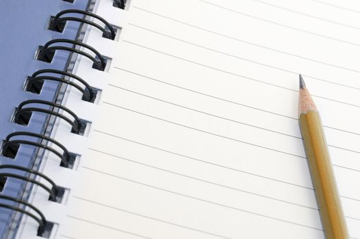 Pencil lying on a blank lined spiral bound notebook with copyspace for your text