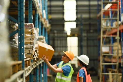 Storehouse employees workers in hardhats and and vests working together in warehouse. Logistics, and manufacture storehouse occupation concept.