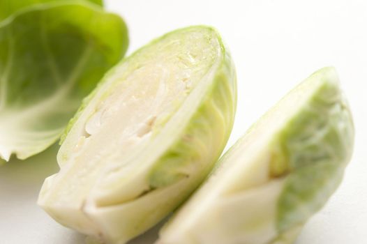 Macro close-up of fresh raw Brussels sprouts cut in half, on white surface background