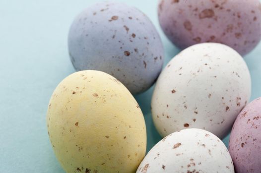 Closeup of five colourful speckled Easter Mini Eggs in sugared candy on a blue background