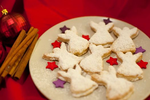 Fresh home baked angel Christmas cookies arranged with colourful stars on a plate on a festive Christmas table