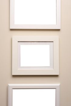 Assorted designs of neutral beige picture frames hanging on a matching colored wall in an art or decor themed background