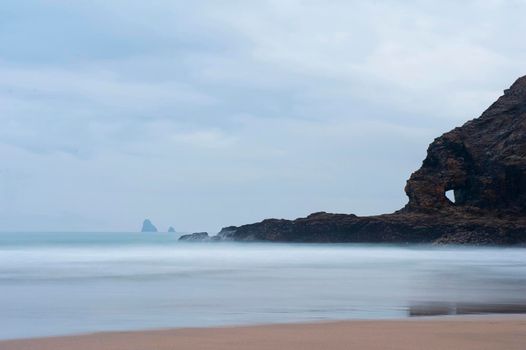 Coastline at Perran Beach, Perranporth, Cornwall with a calm sea on a misty overcast day