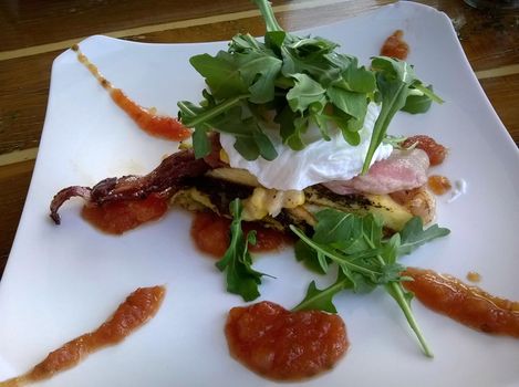 A gourmet restaurant breakfast dish of poached eggs with a healthy green garnish of rocket leaves.