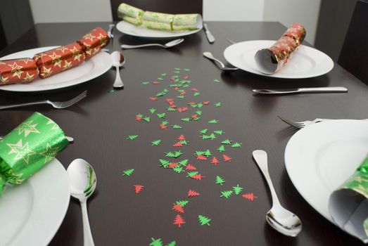 a modern dining table set up for christmas dinner with colorful crackers