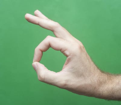Close up Man Hand Showing Okay or Alright Sign Isolated on Green Background.
