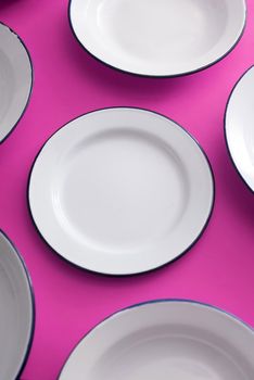 Clean white enamel plates spread out on a purple background in a full frame view for food themes