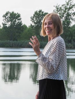 female pensioner having fun and smoking a cigarette in a park - aging free and wellness concept