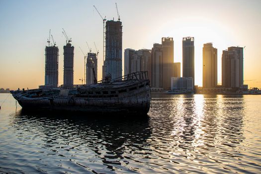 Sunrise in Jadaf area of Dubai, view of Dubai creek Harbor construction of which is partially completed. Old abandoned ships can be seen on the scene. Outdoors