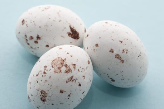 White speckled candy Easter Eggs, closeup view on blue