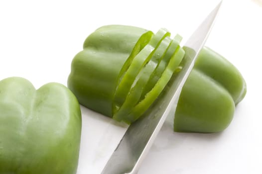Cut green pepper with knife on white background