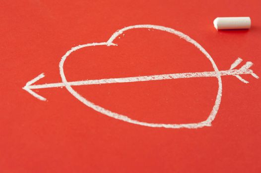 Valentines Day Love background with a chalk sketch of a heart pierced by Cupids arrow on a red background with copy-space