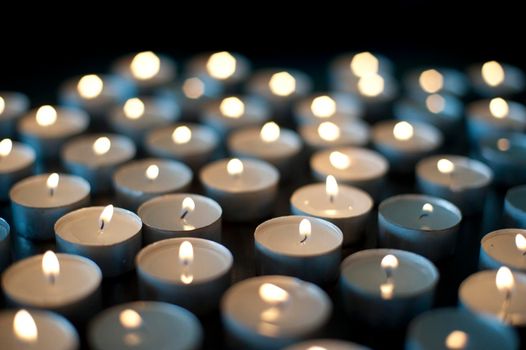 Background of burning candles of rememberance in a church, at a vigil or to celebrate a festival such as Christmas