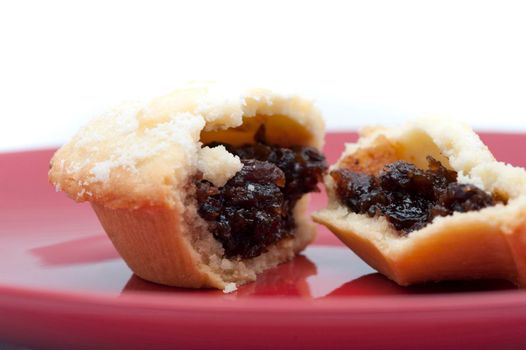 Detail of a fresh fruity Christmas mince pie broken open on a plate to reveal the rich filling of dried fruit and spices