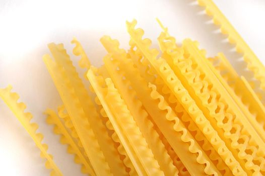 Dried reginette pasta with its distinctive frilly wavy edges for use in traditional Italian cuisine, overhead view on white