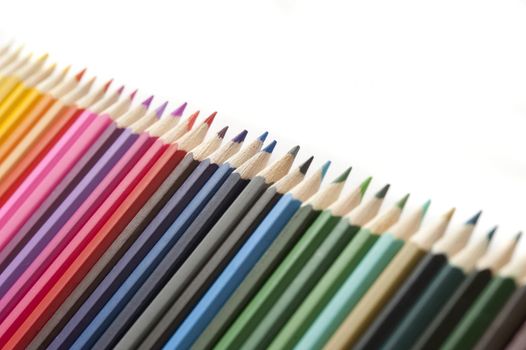Selective focus tight crop on line of various colored pencils with white copy space above them