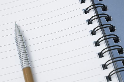 Mechanical pencil lying on the lined blank page of a ringbound notepad