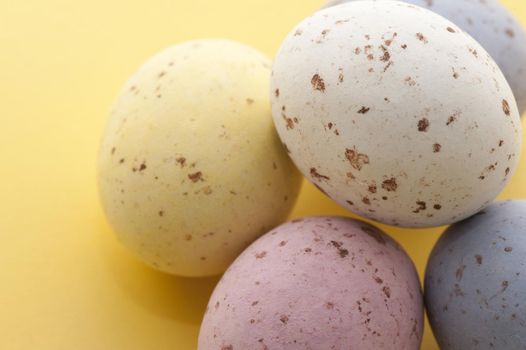Closeup od pastel coloured speckled Easter Eggs on a yellow background