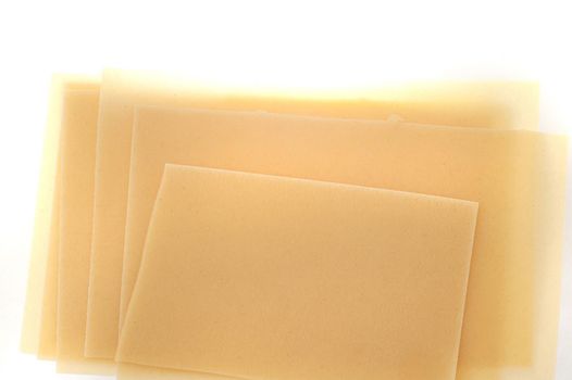 Dried uncooked traditional Italian lasagne sheets made from durum wheat dough on a white background