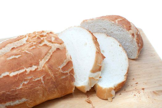 Sliced crispy freshly baked white bread baguette or roll on a bread board, close up view over white with copyspace