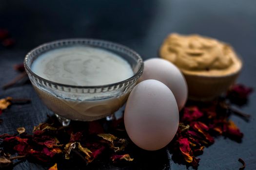 Best DIY face mask of multani mitti or mulpani mitti along with egg white and some yogurt well mixed in a glass bowl on the black wooden surface for the remedy of even skin.