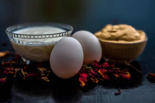 Best DIY face mask of multani mitti or mulpani mitti along with egg white and some yogurt well mixed in a glass bowl on the black wooden surface for the remedy of even skin.