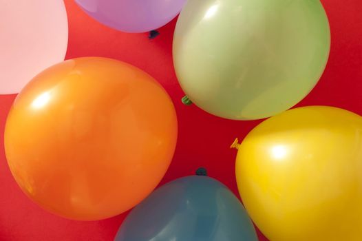 Full frame overhead background of colorful party balloons on red for a festive theme