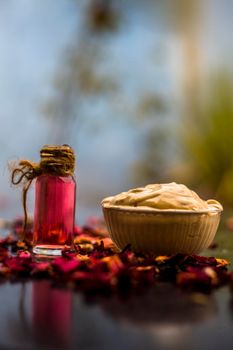 Ubtan/face mask/face pack of Multani mitti or fuller's earth on wooden surface in a glass bowl consisting of Multani mitti and rose water for the remedy or treatment of oily skin.On wooden surface.;