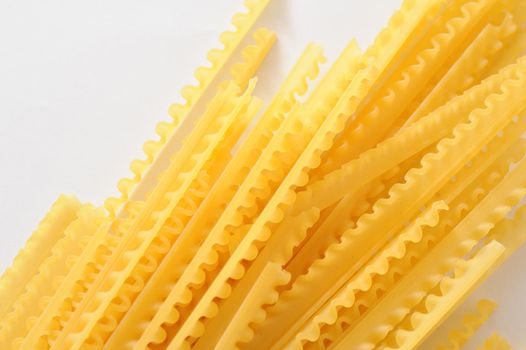 Dried reginette Italian pasta with its frilled wavy edges on a white background, overhead view with copyspace